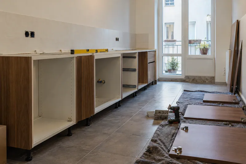 Visualización conceptual IA: Módulos de cocina en montaje con puertas pendientes de colocar.